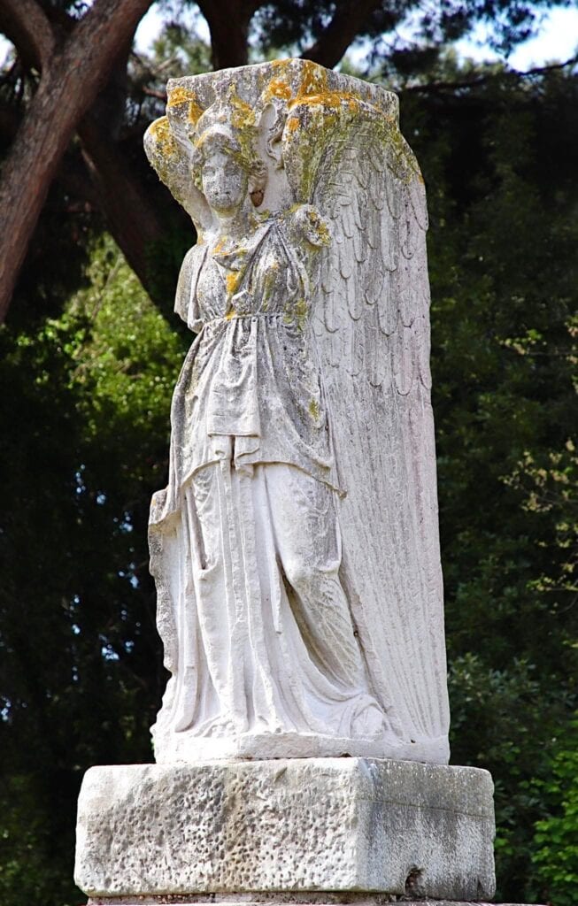 A cast of an ancient sculpture displayed outdoors among the archaeological remains of Ostia Antica.